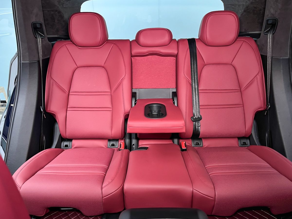 Porsche Cayenne rear seats with Burgundy custom-fit seat covers showing rear bench fit, center armrest, cupholder and seat belt access